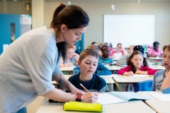 Multi-ethnic schoolgirls and shcoolboys sit into the class for their first day at school. Some of them are shy and other expressive.  There is multicolour name in the front of the desk. Photo was taken in public school in Canada.